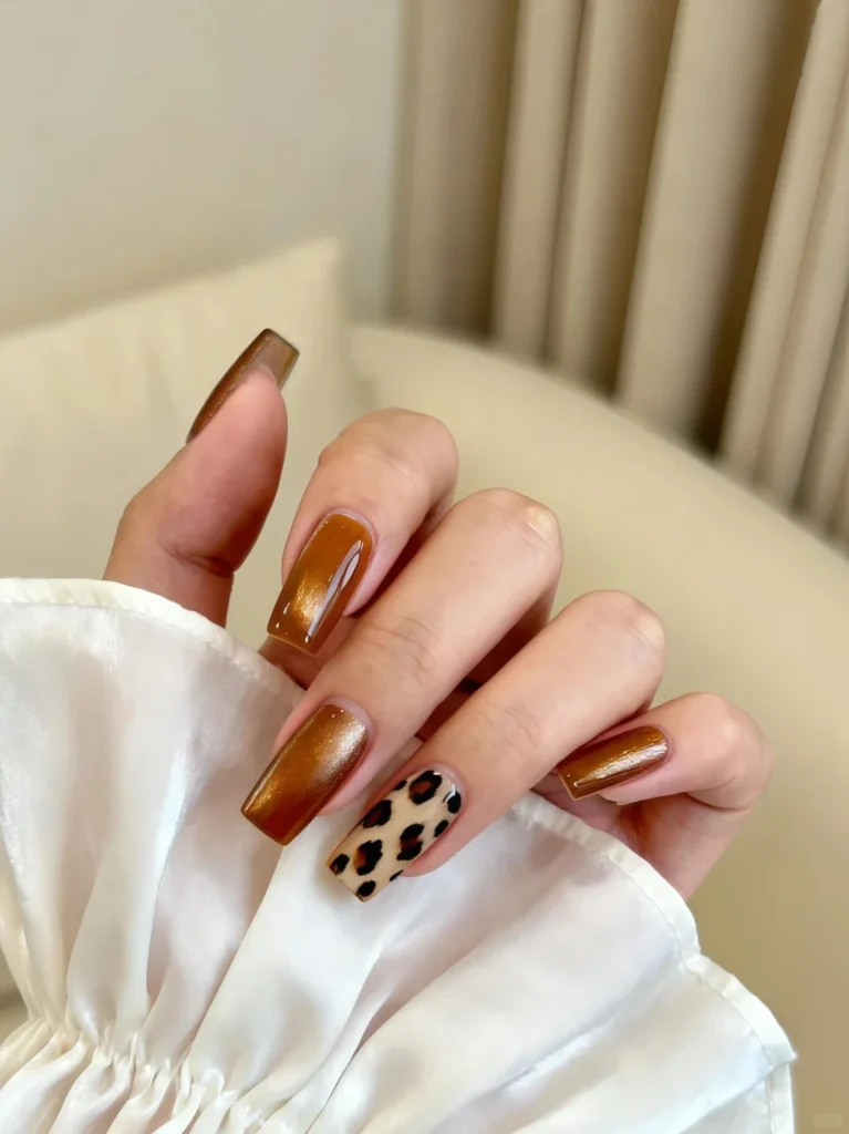 Shiny brown nails combined with leopard print accent design.