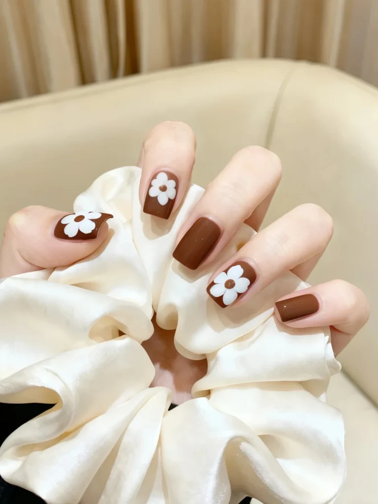 Soft nude nails decorated with white floral patterns.
