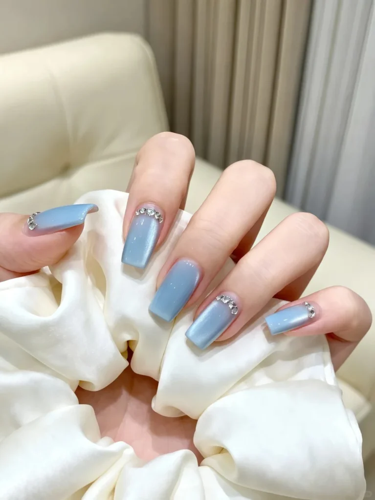 Shiny pastel blue nails with transparent glossy texture.